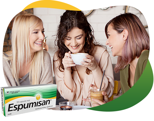 Three girlfriends drinking coffee and having a good time, sharing information about flatulence and Espumisan.There is a packshot of Espusiman 40 mg Capsules in the front.